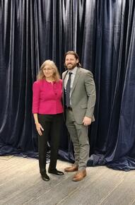 Rashmi Luthra and Scott Ham stand in front of a curtain background