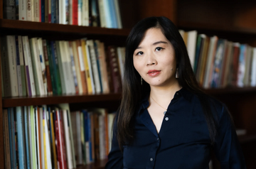 Photo of a woman with long hair in front of a bookshelf